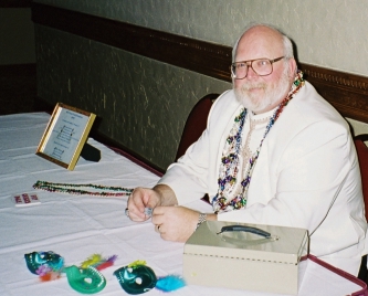 Image: Man sitting at a table holding several masks.