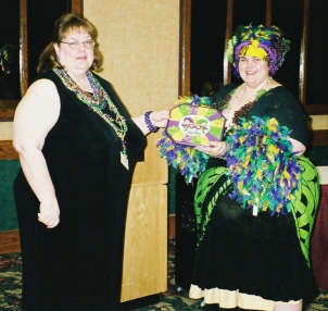 Image: One woman presenting a plaque to another, in costume.