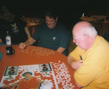 Image: People at a table working on a jigsaw puzzle.