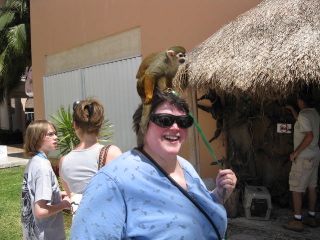 Image: laughing woman with a monkey on her head.